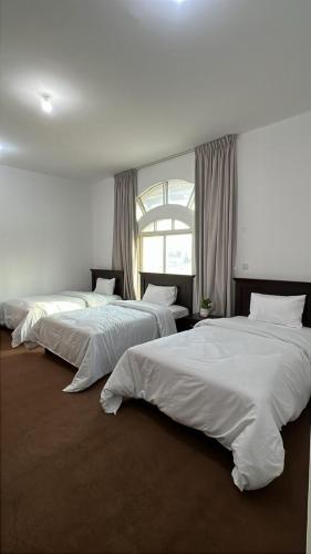 three beds are lined up in a room at Triple Room with 3 Single Beds A1 in Abu Dhabi