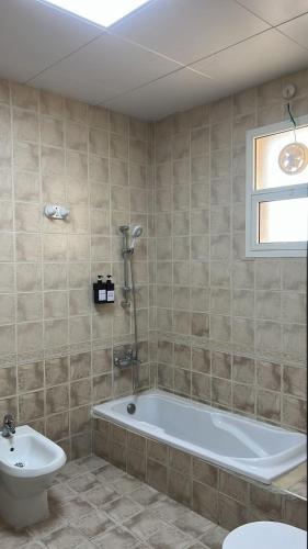 a bathroom with a tub and a toilet and a sink at Triple Room with 3 Single Beds A1 in Abu Dhabi