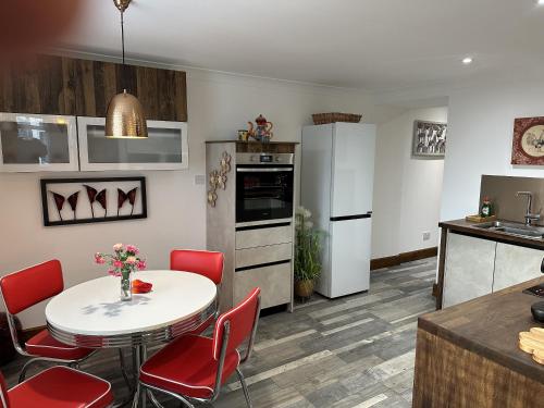 een keuken met een witte tafel en rode stoelen bij Sealladh Sona in Inverness