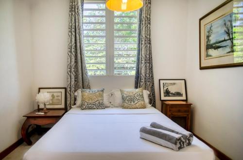 a bedroom with a white bed with a window at Private Villa Azure Garden with pool in Grand Baie