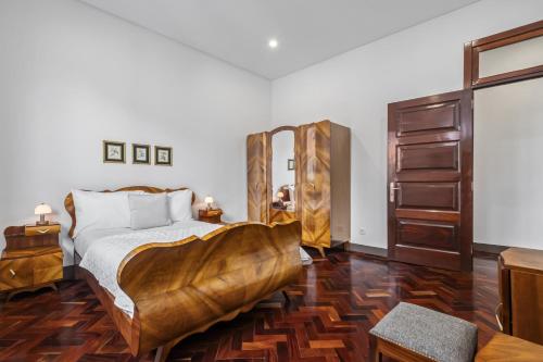 een slaapkamer met een groot bed met een houten vloer bij Reis by KAAMAH in Ribeira Brava