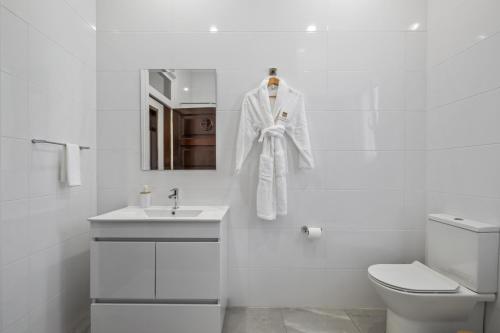 een badkamer met een witte badjas aan de muur bij Reis by KAAMAH in Ribeira Brava