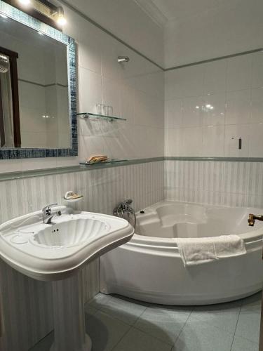 a white bathroom with a sink and a tub at Complejo Hostelero Paladium in Villamartín