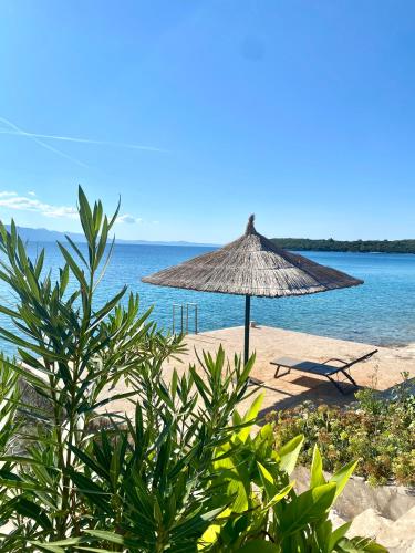 een strand met een rieten parasol en stoelen en de oceaan bij Villa Noma in Lovište