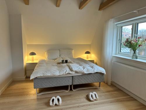 a bedroom with a bed with two lamps and slippers at Modern & Unique property in Odense centrum - FREE PARKING in Odense