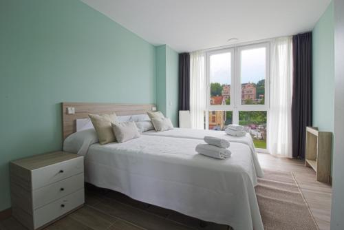 ein Schlafzimmer mit einem großen weißen Bett mit Handtüchern darauf in der Unterkunft Apartamentos Turísticos La Pontificia in Comillas