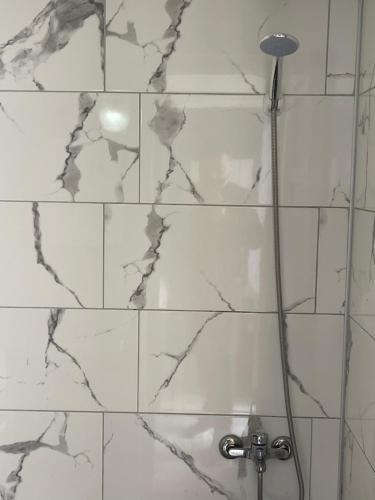 een badkamer met een douche en witte marmeren tegels bij Karya Hotel in Kuşadası