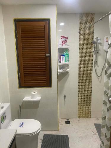 a bathroom with a toilet and a shower with a window at Sea Sand Sun Condominium in Ban Bang Nok