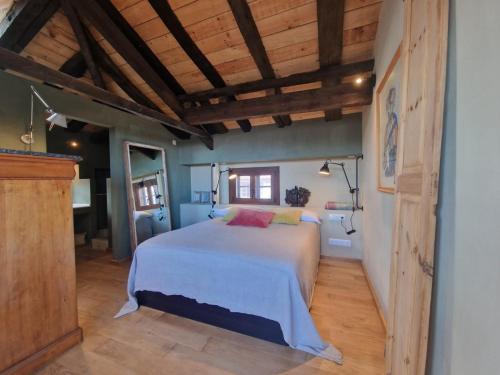 een slaapkamer met een bed in een kamer met houten plafonds bij Apartamento La Buhardilla in Llanes