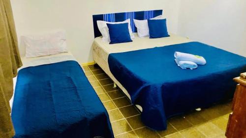 サルバドールにあるPPousada 03 min da praia, Itapuaのベッドルーム1室(青いシーツが備わるベッド2台付)