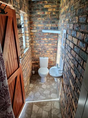 a brick bathroom with a toilet and a sink at Malkop Sea View Resort in Lambertʼs Bay