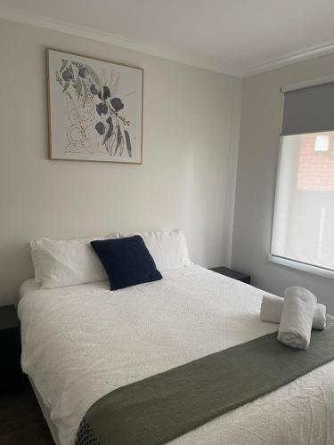 een slaapkamer met een wit bed en een blauw kussen bij Frankston Vacation Home in Frankston East