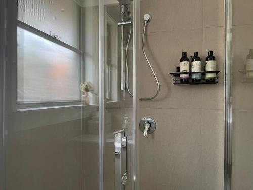 een douche met een glazen deur met flessen op een plank bij Frankston Vacation Home in Frankston East