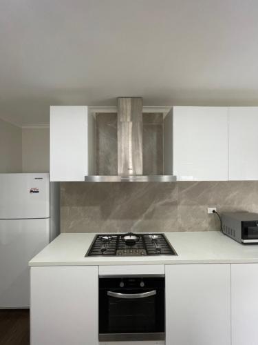 a kitchen with white cabinets and a stove top oven at Frankston Vacation Home in Frankston East