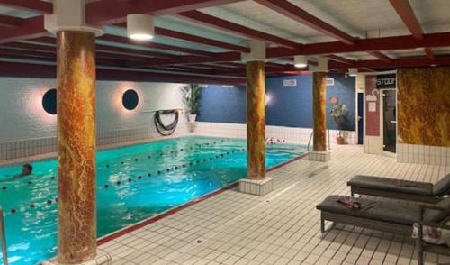 a large swimming pool with blue water in a building at Hotel Restaurant De Zwaan in Raalte
