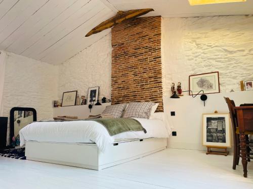 ルゼにあるSolar - Maison de pêcheurのベッドとレンガの壁がある寝室
