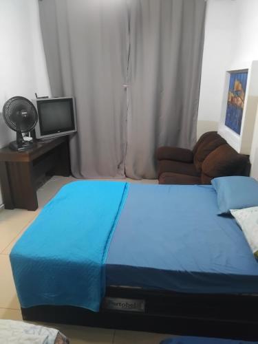 una camera da letto con un letto blu e una televisione di Nova Casa Studio Mega - Qto1 c Ar - 3 Vagas Garagem - Esp Térreo Priv - WiFi 300 Megas - Home Office a 200 mts Praia da Pompéia a Santos