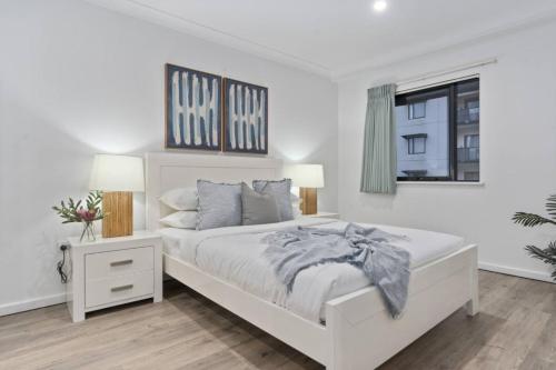 een witte slaapkamer met een wit bed en een raam bij Cityscape on Mounts Bay in Perth