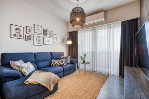 a living room with a blue couch and a large window at Gharghur Apartment - Baby Gear, Office & Parking in Għargħur