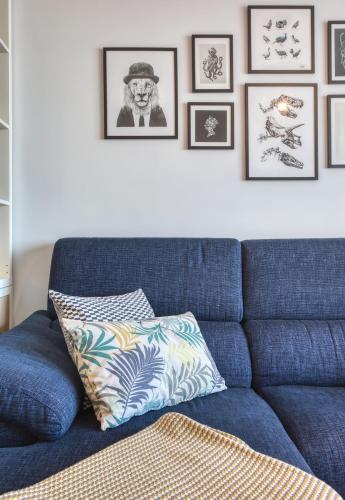 a blue couch in a living room with pictures on the wall at Gharghur Apartment - Baby Gear, Office & Parking in Għargħur