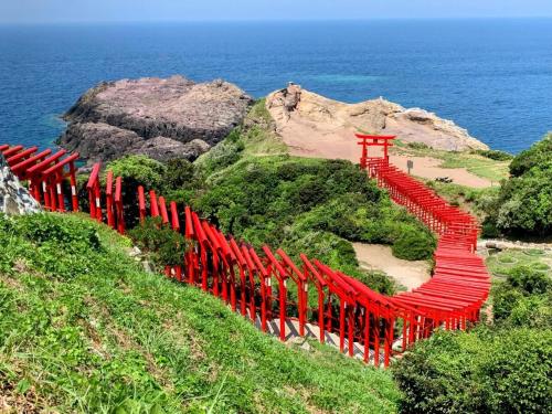 una valla roja en una colina junto al océano en インジホテル下関, en Shimonoseki