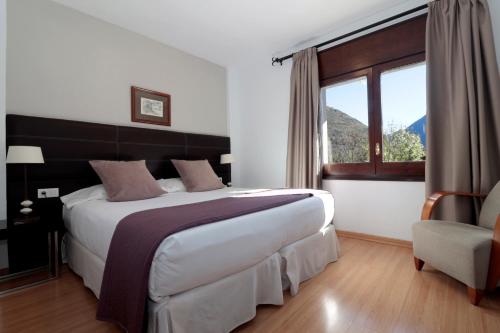 Un dormitorio con una cama grande y una ventana grande. en Hotel Blu Aran, en Vielha