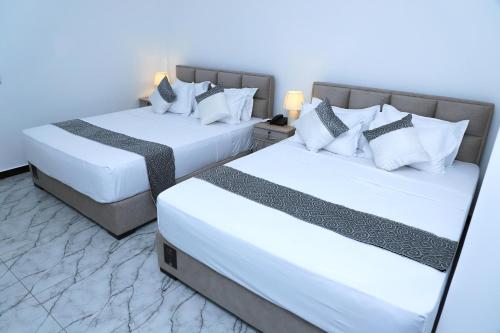 ネゴンボにあるThe Galaxy Airport Hotelの白い枕が置かれたホテルの部屋にはベッドが2つある
