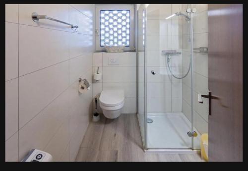 a white bathroom with a toilet and a shower at Ferienwohnung Seesternchen am Deich2 C46 in Norden