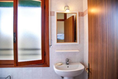 un baño con lavabo y espejo en Downtown apartment by the beach, en Eraclea Mare