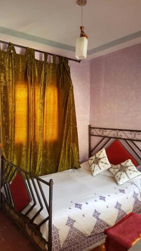 a bedroom with a bed with a gold curtain at Kasabah Senhaji in Moulay Idriss Zerhoun