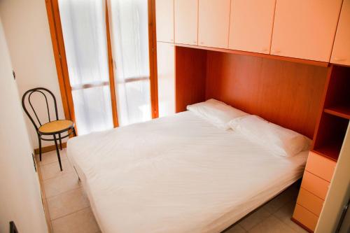 um pequeno quarto com uma cama branca e uma cadeira em Ground-floor haven just 350mt from the beach em Eraclea Mare