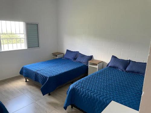 - 2 lits dans une chambre avec des draps bleus dans l'établissement Sitio Recanto dos Passáros, à Caçapava