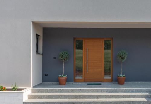 a wooden door with two potted plants in front of a house at Villa Valpinia Luxury Villa in a Quiet Location with Pool, Sauna, Jacuzzi and Large Garden in Martinski
