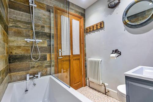 ein Badezimmer mit einer Badewanne, einem WC und einem Spiegel in der Unterkunft Finest Retreats - No 3 Sandside in Whitby