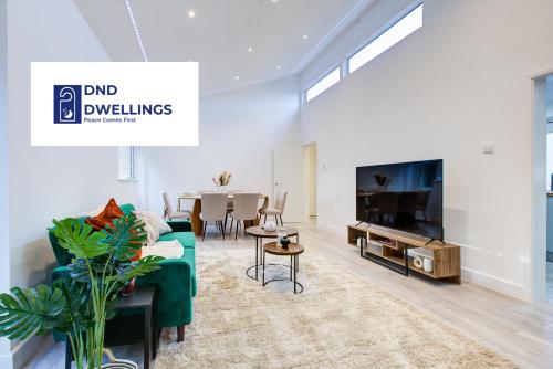 a living room with a green couch and a tv at Sleek 3 Bedroom Home Sleeps 6 with Parking in Colchester