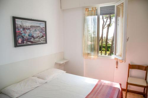 een slaapkamer met een bed, een raam en een stoel bij Spacious first-floor flat near the beach in Eraclea Mare