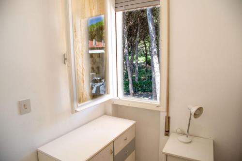 een witte kamer met een raam en een bureau met een lamp bij Spacious first-floor flat near the beach in Eraclea Mare