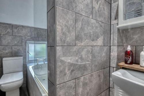 a bathroom with a sink and a toilet and a tub at Stylish 2BR Cottage Pet-Friendly with Free Parking in Partington
