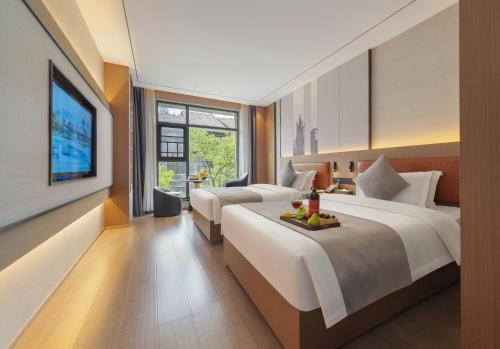 a hotel room with two beds and a television at 柯凡酒店-About 3 kilometers from the East Gate of Zhangjiajie Forest Park, English service, free recommended travel routes, ticket purchase in Zhangjiajie