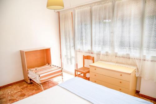 Un dormitorio con una cama y una cómoda y una ventana. en Central apartment at 250mt from the sea, en Eraclea Mare
