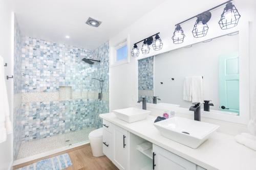 uma casa de banho branca com 2 lavatórios e um chuveiro em West End's Famous Comfy Sloth em Roatan