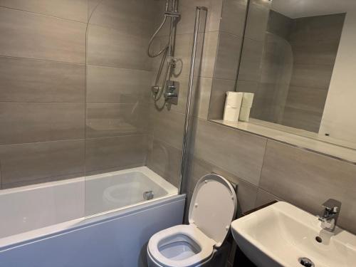 a bathroom with a toilet and a tub and a sink at 505 City Centre Stylish Double Apartment in Birmingham