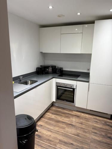 a kitchen with white cabinets and a wooden floor at 505 City Centre Stylish Double Apartment in Birmingham