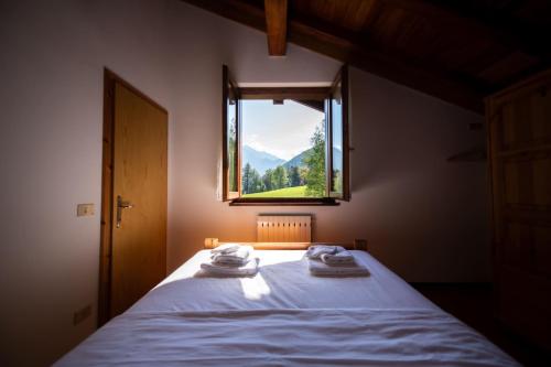 a bedroom with a bed with a window with a view at Appartamenti Lembondel - Ledro in Tiarno di Sotto