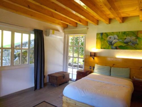 Un dormitorio con una cama en una habitación con ventanas. en Hotel Boutique Frutos del bosque de Zacatlan, en Jicolapa