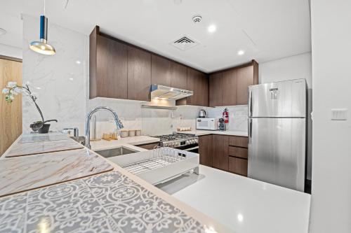a kitchen with wooden cabinets and a stainless steel refrigerator at Contemporary 1BR City View Apartment at 1 Residence in Dubai
