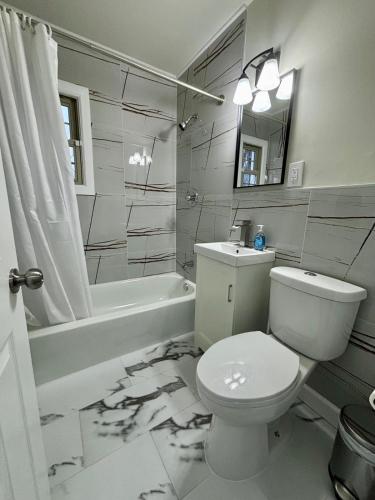 a bathroom with a toilet and a tub and a sink at Cozy Home Near Dearborn in Detroit
