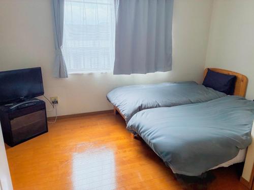 a bedroom with a bed and a flat screen tv at ゲストハウスレポーレ山大前 in Yamaguchi