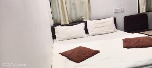 a bedroom with a white bed with white pillows at hotel VIJAY in Mount Ābu