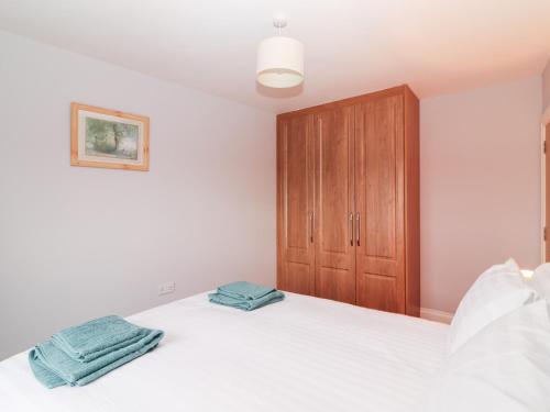 a bedroom with a white bed and a wooden cabinet at 1 Windermere in Kinvara